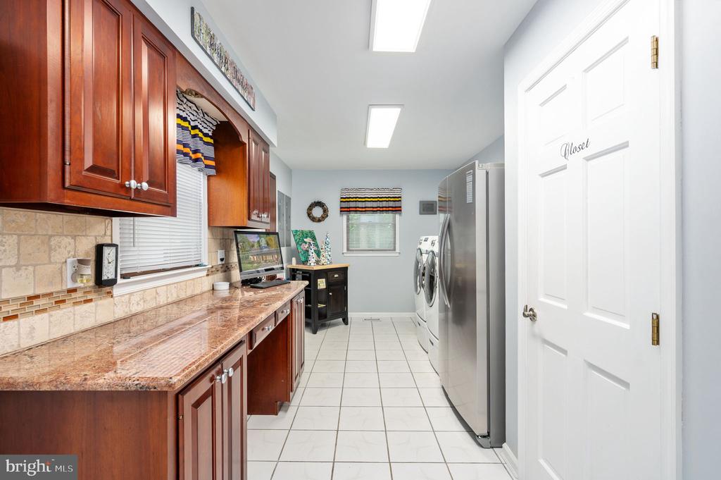 Laundry room with wood cabinetry, a long countertop, and washer and dryer.