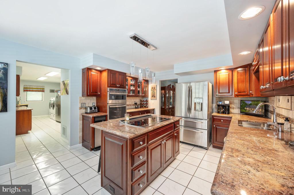 Kitchen with cherry cabinets, granite counters, a cooktop island, and stainless steel appliances.