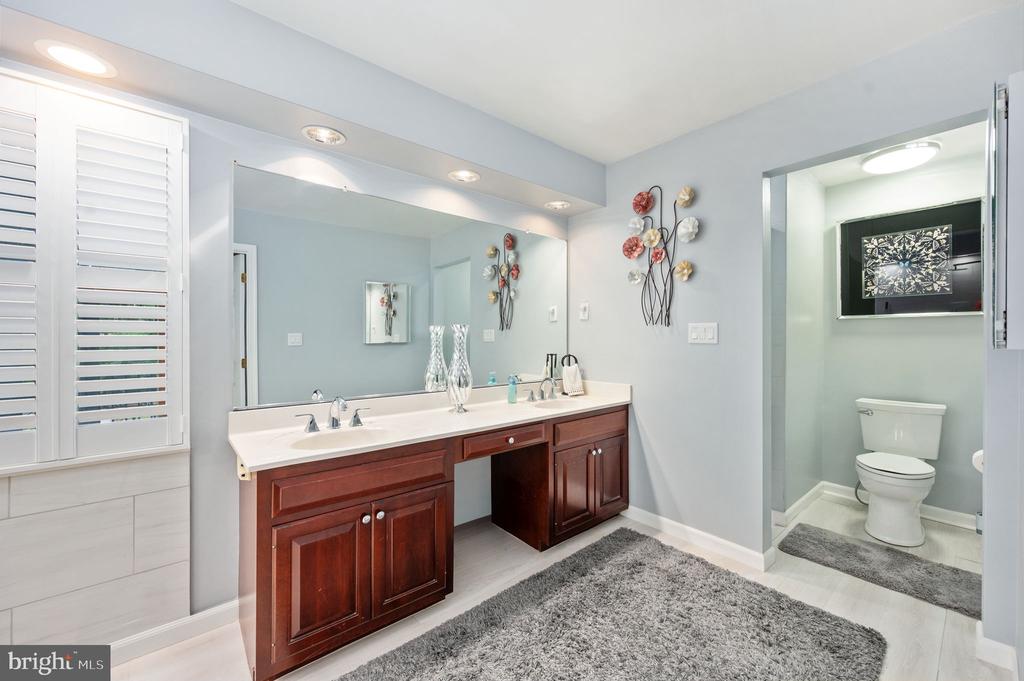 Bathroom with a dark wood double vanity, large mirror, and separate toilet nook.