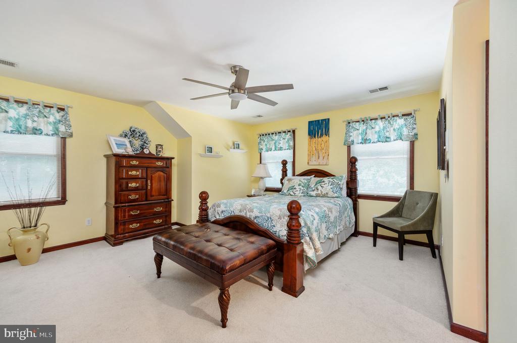 Bedroom with a dark four-poster bed, floral bedding, and a tufted leather bench.