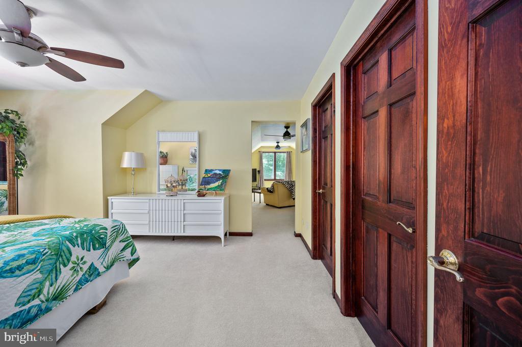 Bedroom with tropical-leaf bedding, a white dresser, and dark wood doors.