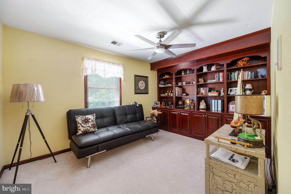 Furnished den with a black leather sofa and built-in dark wood bookcases.