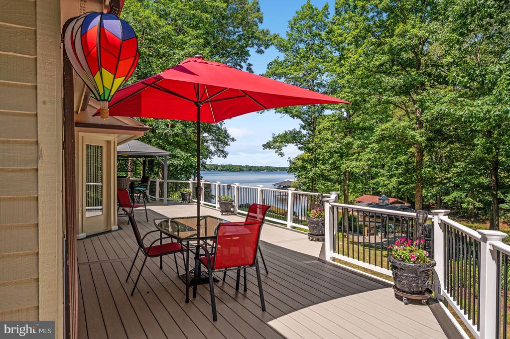 Deck with red umbrella and seating overlooking a lake.