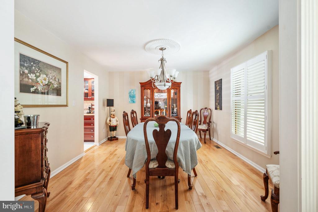 Dining room with a long table, carved chairs, glass-front china cabinet, and hardwood floors.