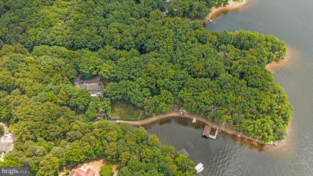 Wooded waterfront property with a house and dock along a sheltered cove.