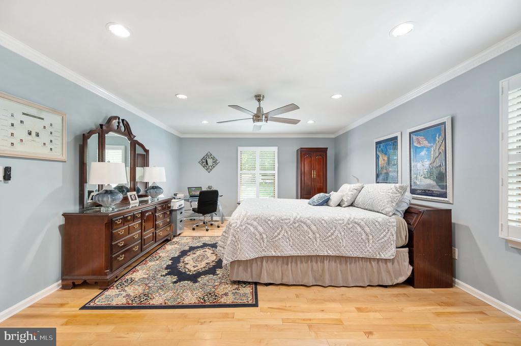 Bedroom with a large bed, dark wood furniture, and a patterned rug on hardwood flooring.