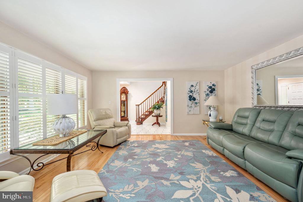 Living room with a green leather sofa, cream recliner, blue floral rug, and doorway to a wooden staircase.