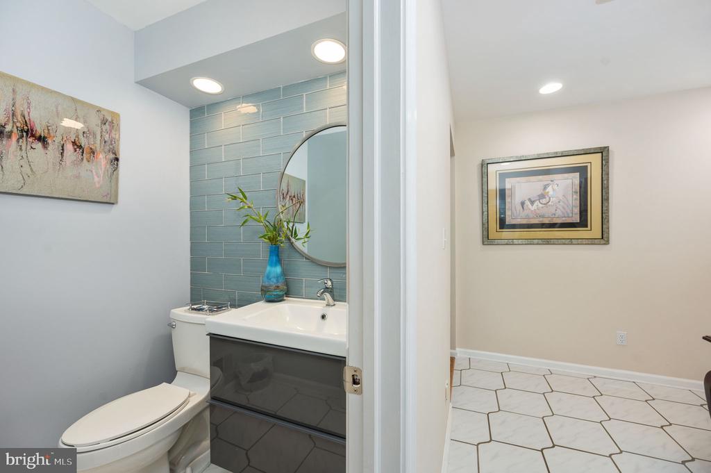 Bathroom with blue-green tile behind the vanity and a doorway to an adjoining tiled room.