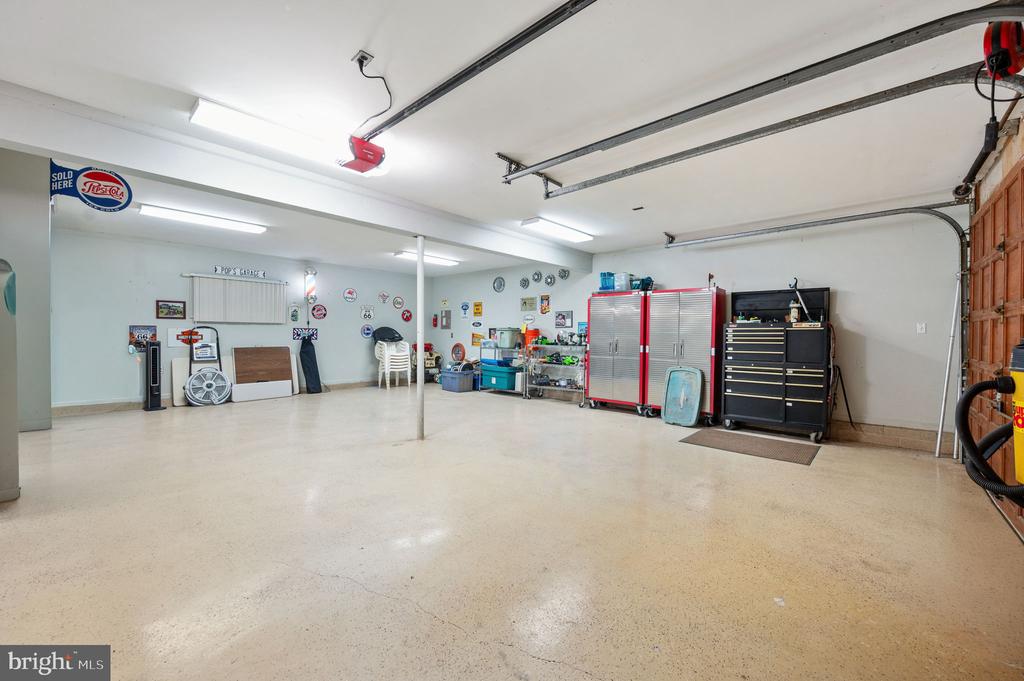 Spacious garage with overhead door tracks, a center support post, and red and black tool cabinets.