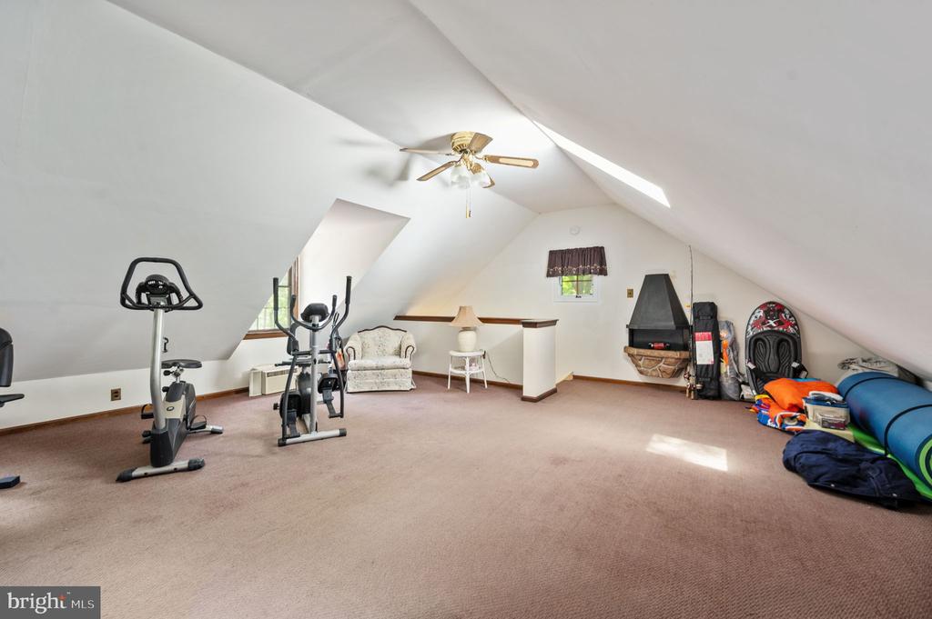 Attic bonus room with exercise equipment, a small sitting area, and a fireplace.