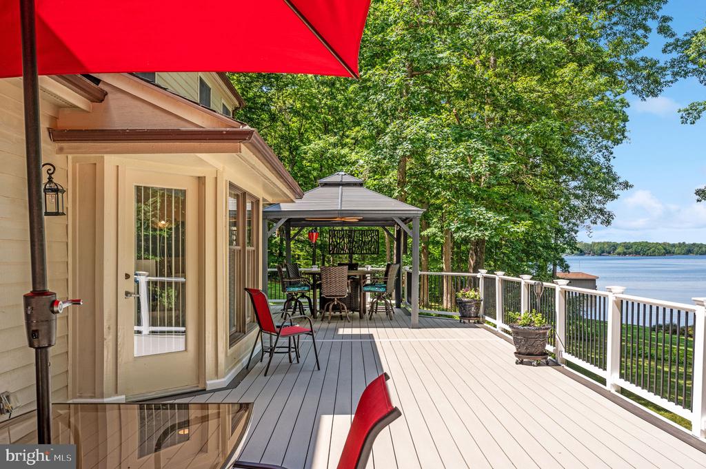Waterfront deck with a covered gazebo and red umbrellas overlooking the lake.