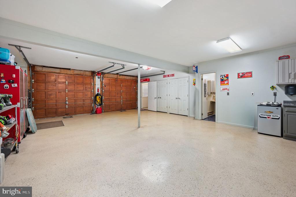 Spacious garage with two wooden doors, a speckled floor, and storage shelves.