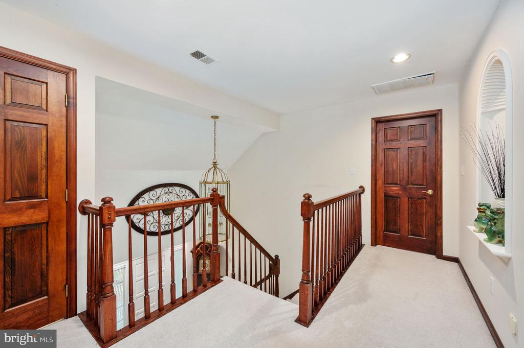 Upstairs landing with dark wood stair railings, paneled doors, and a hanging lantern.