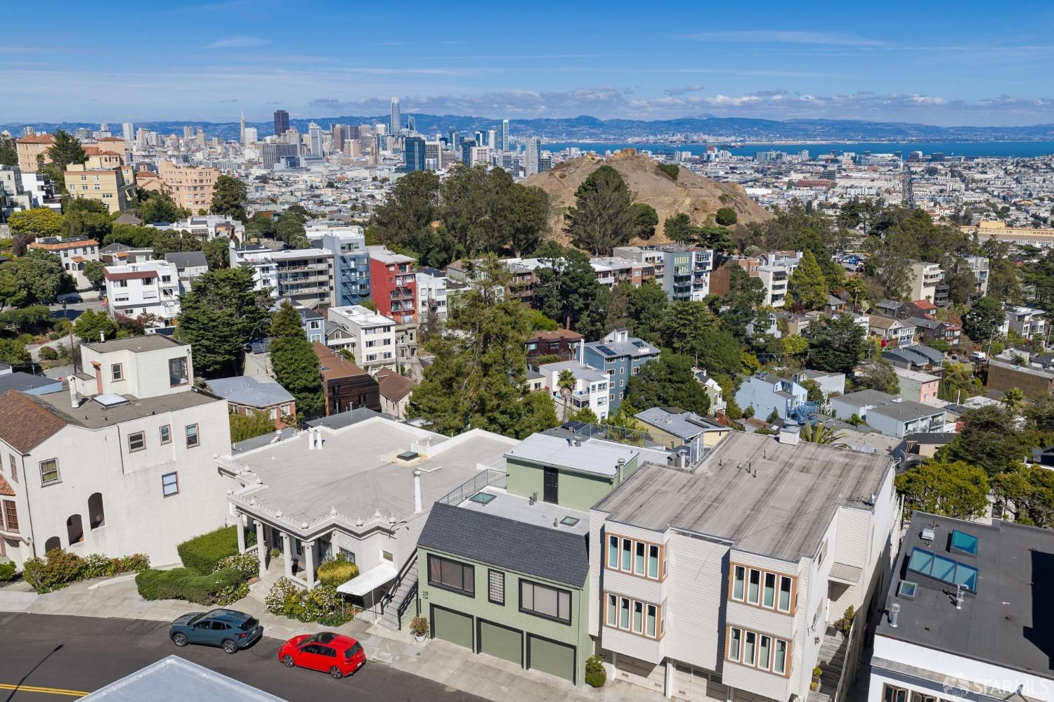 Aerial view of San Francisco homes, hillside, downtown skyline, and bay.