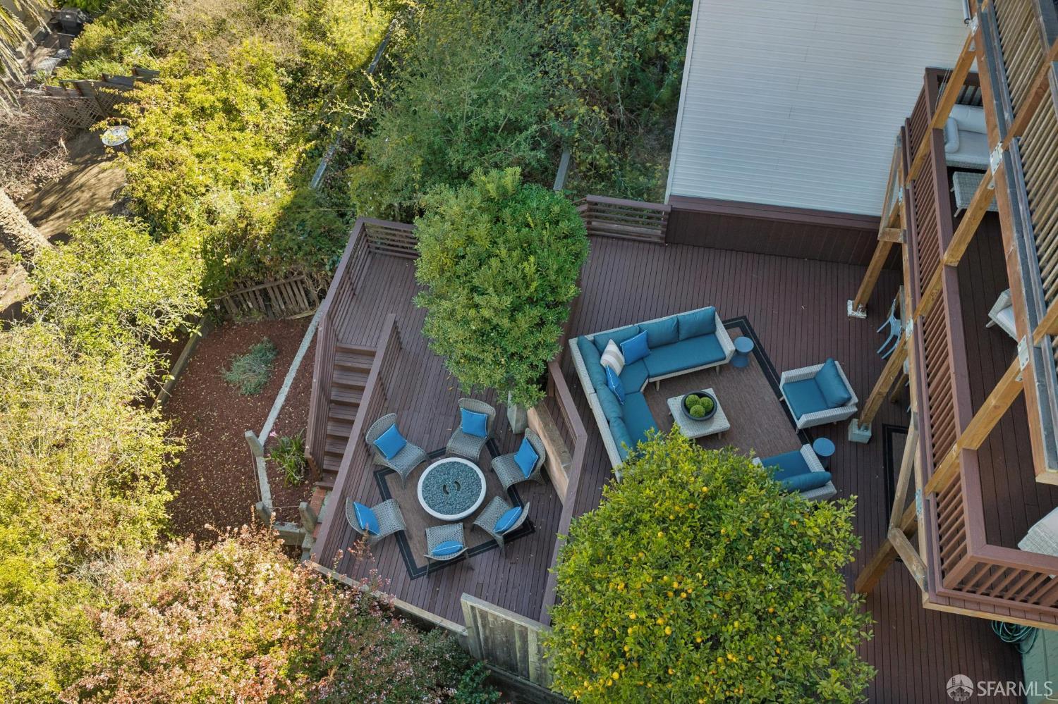 Aerial view of a wooden deck with blue outdoor seating and lush garden greenery.