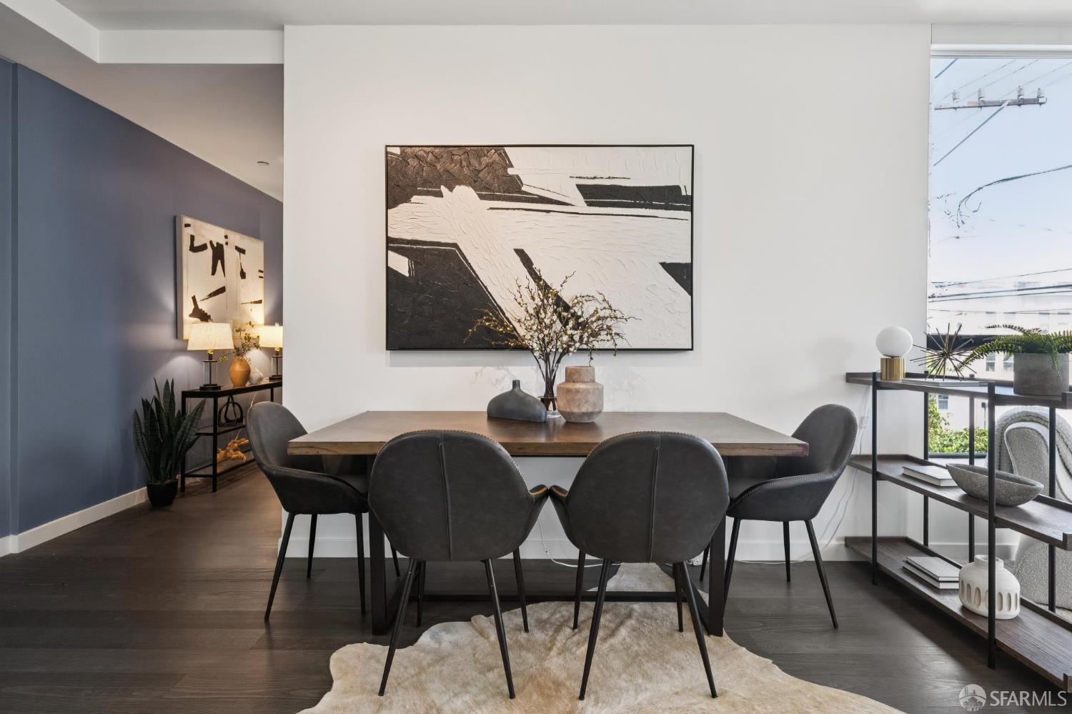 Staged dining room with charcoal chairs, abstract wall art, and large windows.