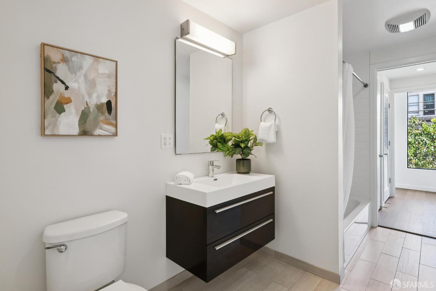 Bathroom with a dark floating vanity and a shower visible through the doorway.