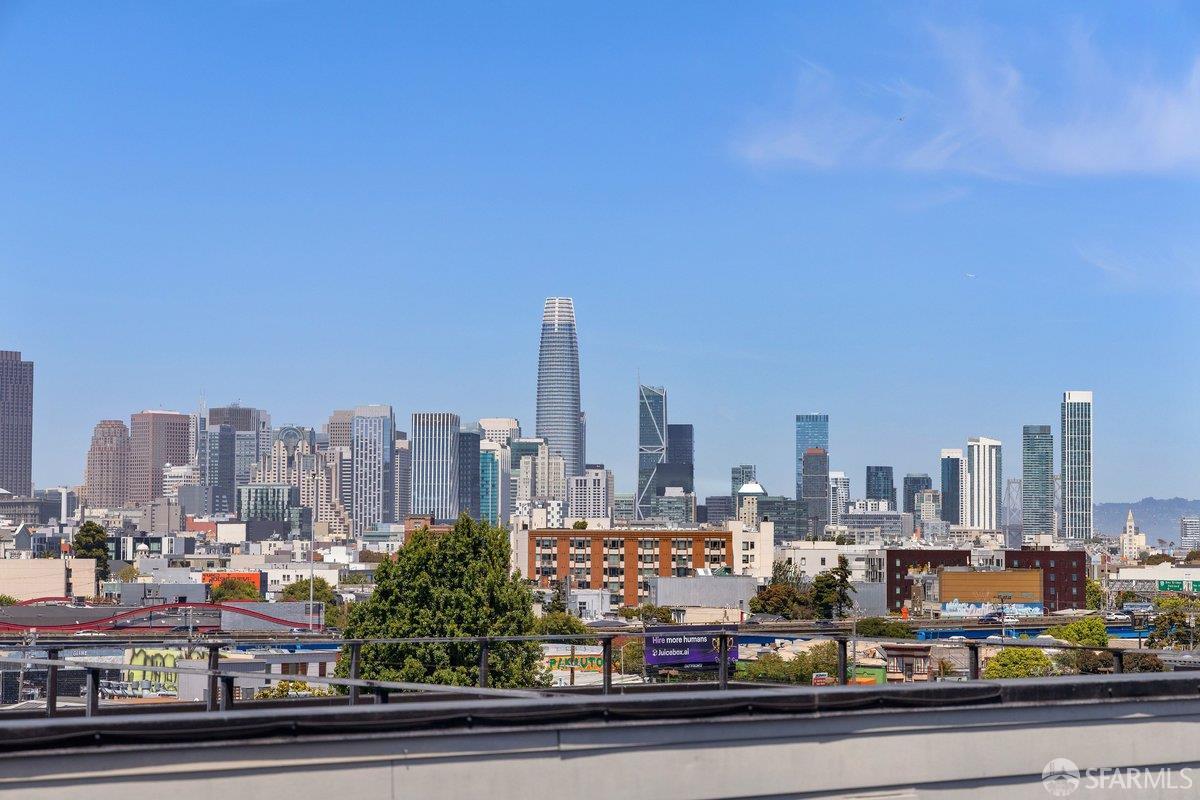 San Francisco skyline with Salesforce Tower rising above rooftops, viewed from behind a terrace railing.