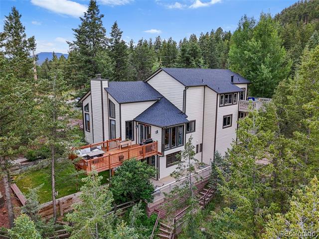 Multi-level house with wooden decks nestled among trees on a wooded hillside.
