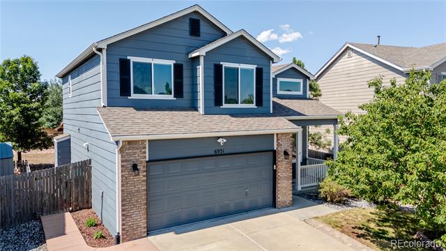 Two-story blue-gray house with a double garage, brick accents, and a concrete driveway.