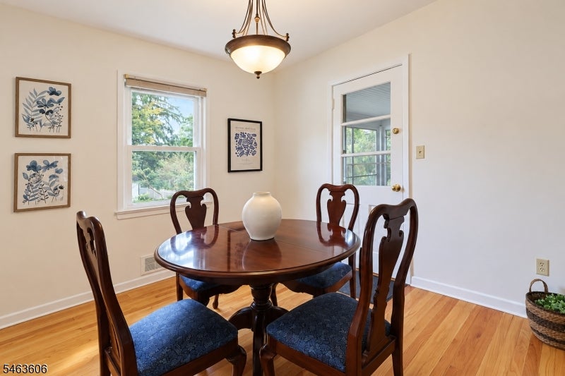 Dining room with an oval wood table, blue-seat chairs, and honey-toned hardwood floors.