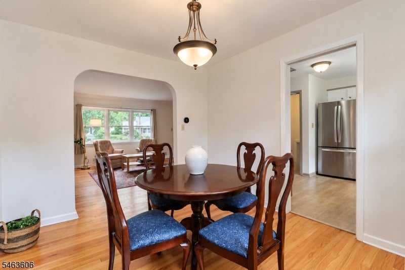 Dining room with a round wooden table, blue chairs, and an archway to the living room.