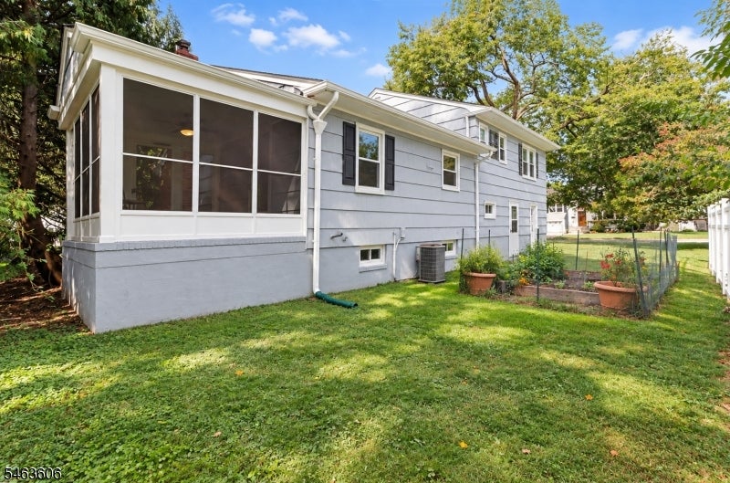 Rear exterior of a gray-sided home with a screened porch and fenced garden.