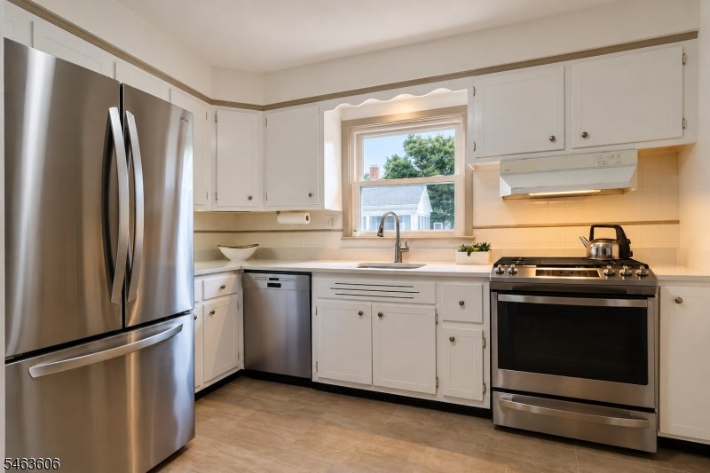 Kitchen with white cabinets, stainless steel appliances, and a sink beneath a window.