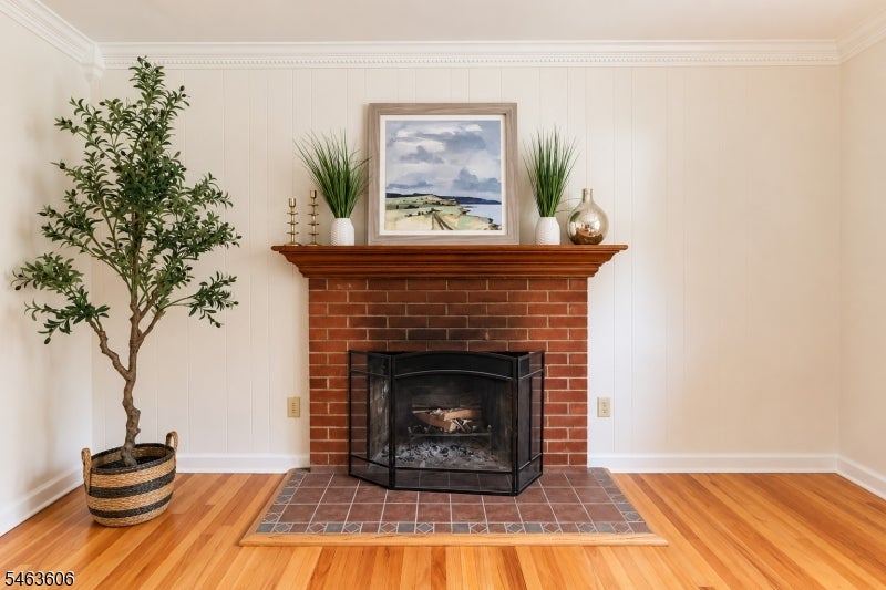 Living room with a brick fireplace, tiled hearth, and hardwood floors.
