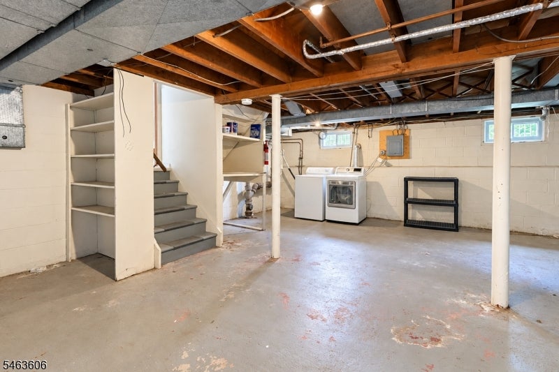 Unfinished basement with exposed ceiling joists, concrete floor, staircase, and washer and dryer.
