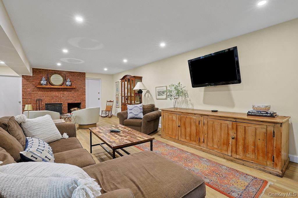 Living room with brown sectional sofas, a brick fireplace, and a wall-mounted television.