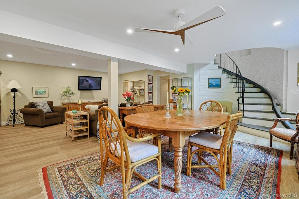 Dining and living area with a round wooden table, patterned rug, and curved staircase.
