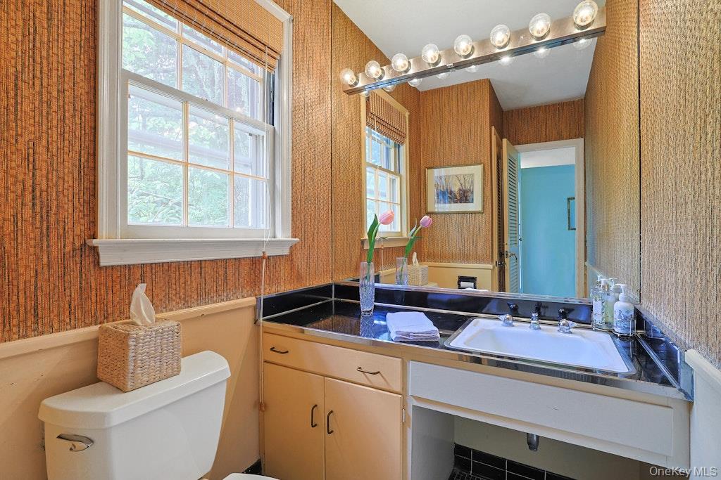 Bathroom with woven-texture walls, a large mirror, and a black countertop beneath a window.