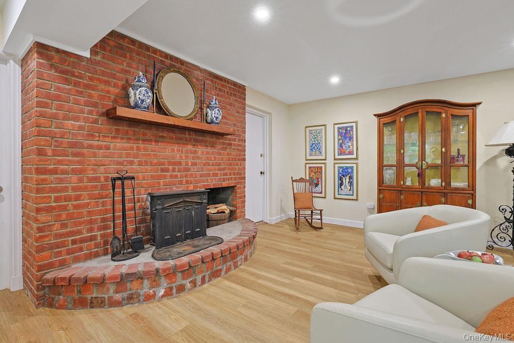 Living room with a curved brick fireplace, white seating, and a glass-front wooden cabinet.