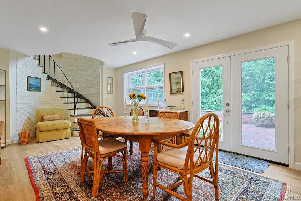 Dining room with a round wooden table, curved staircase, and glass doors opening to a patio.
