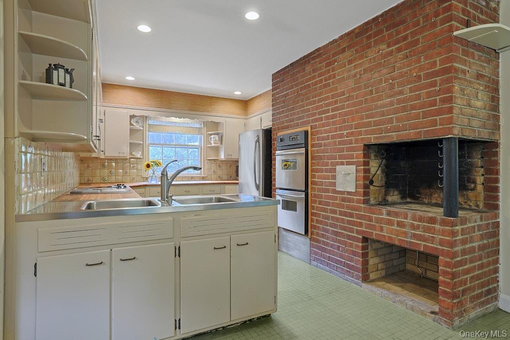 Kitchen with cream cabinetry and a large red brick fireplace with a cooking hearth.