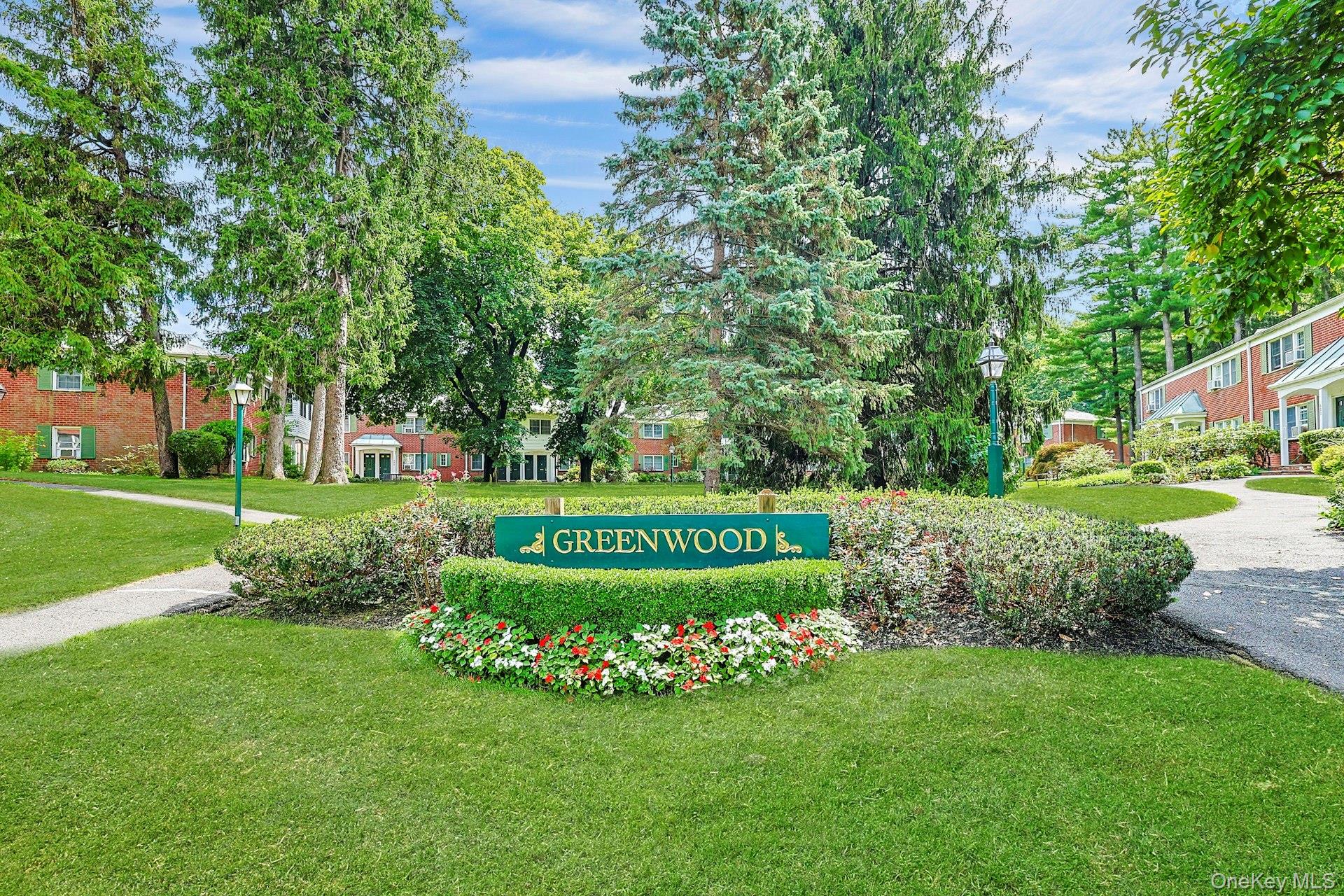 Greenwood residential complex entrance, with brick buildings, landscaped grounds, and a sign bearing its name.