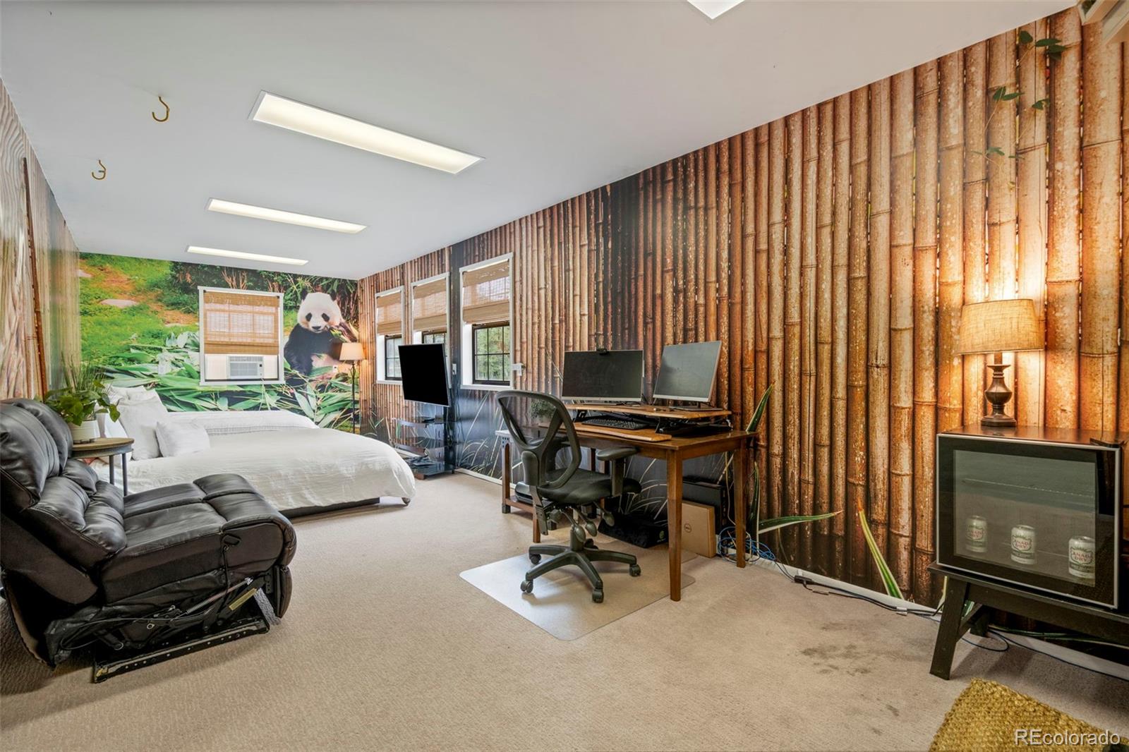 Bedroom with a panda mural, bamboo-patterned walls, white bed, and computer workstation.