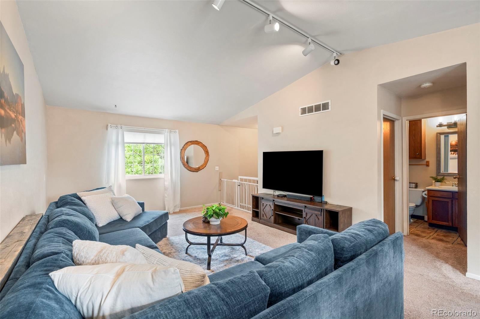 Living room with blue sectional sofas, a round coffee table, and a television beside a window.