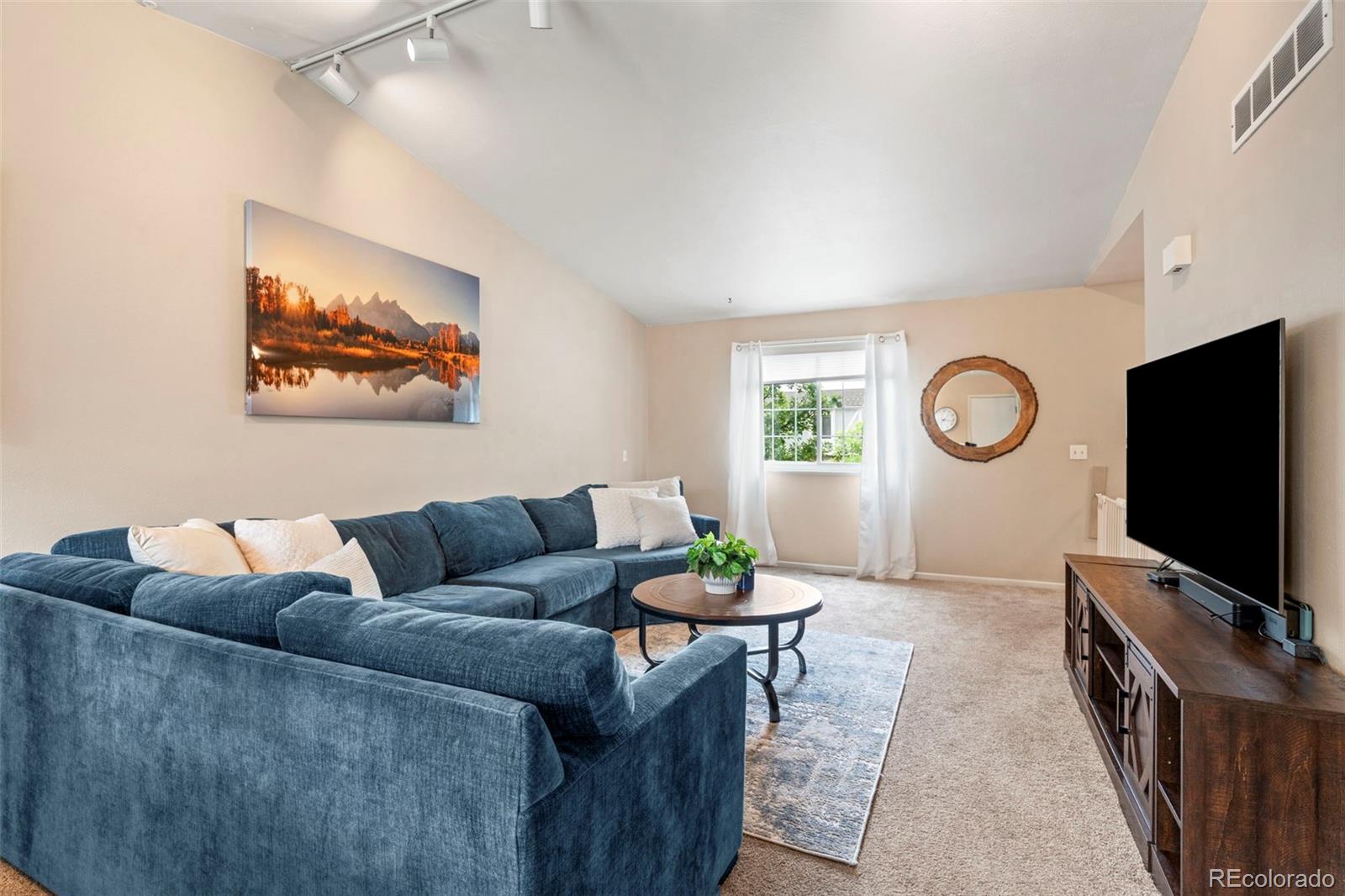 Living room with a blue sectional sofa, round coffee table, and large television.