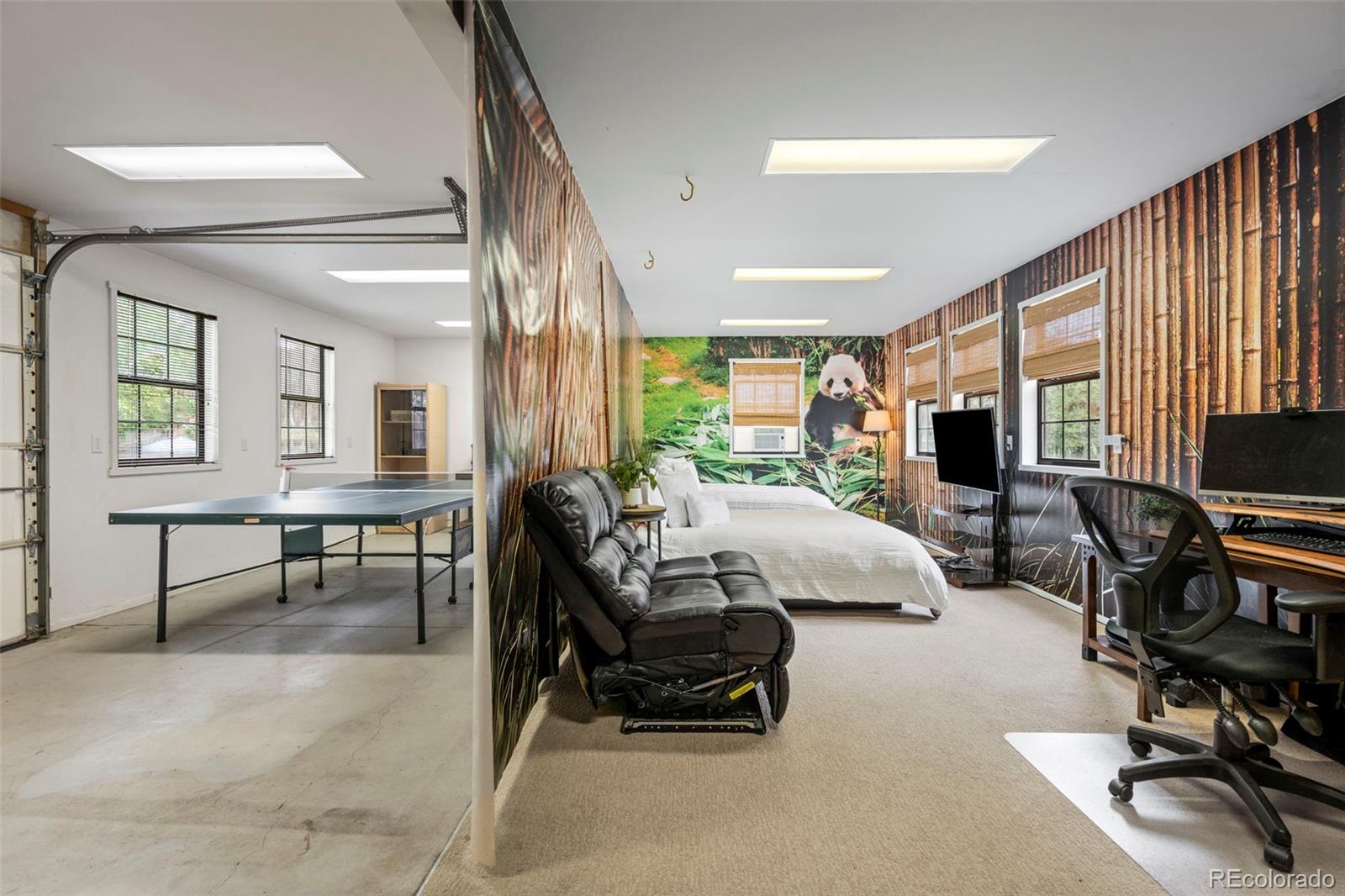 Finished garage with a ping-pong table beside a furnished bedroom and office with a panda mural.
