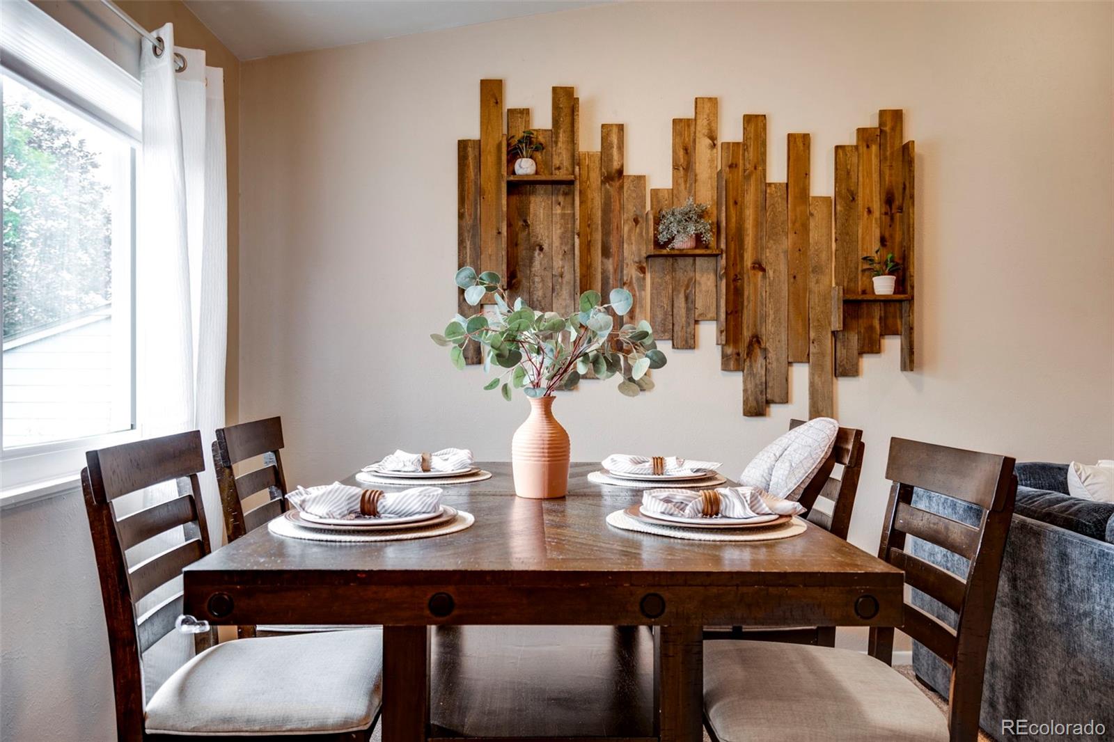 Dining room with a set table, dark wooden chairs, and rustic wood wall art.