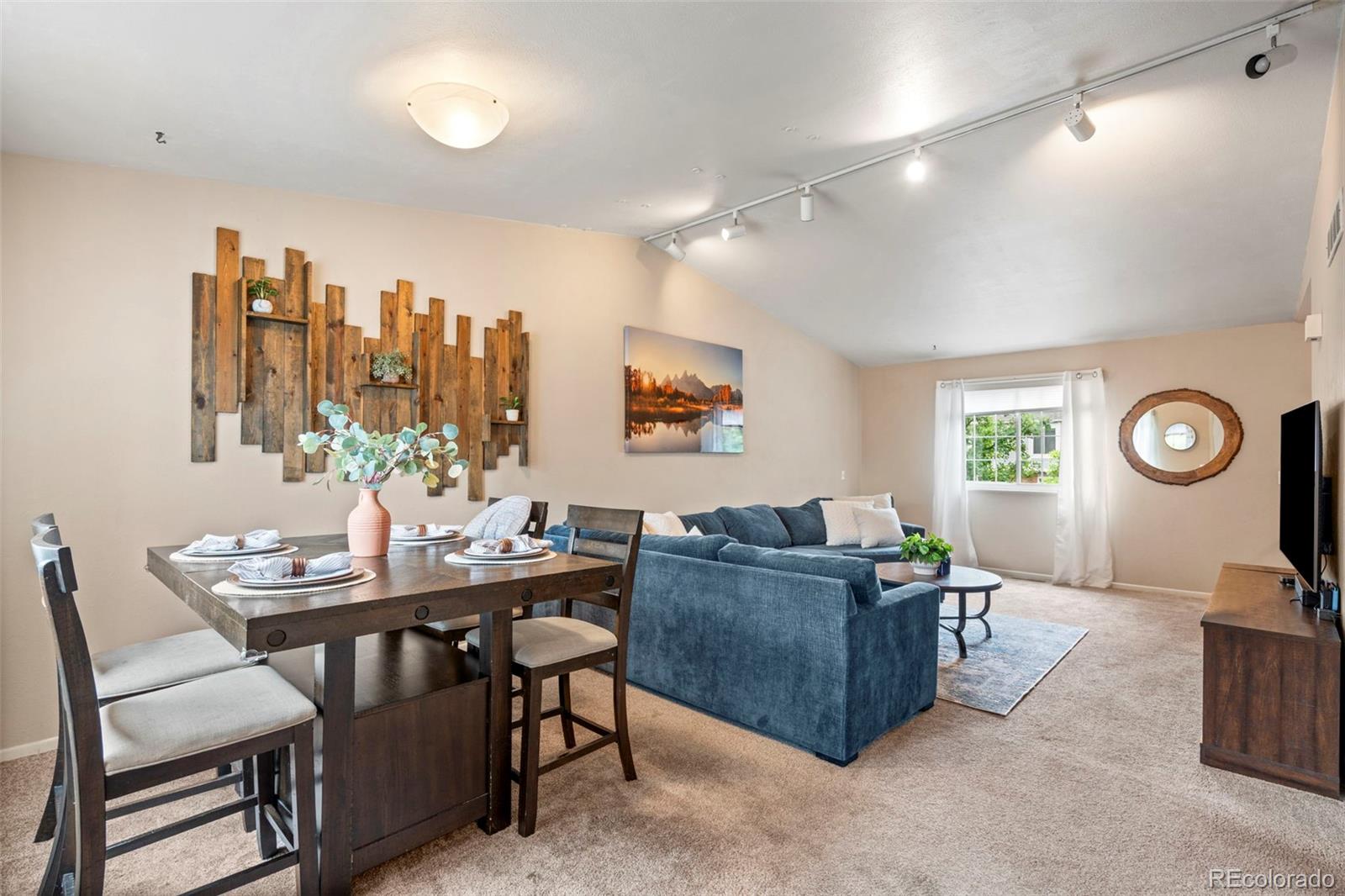 Open-plan living and dining room with a blue sectional and dark wood dining table.