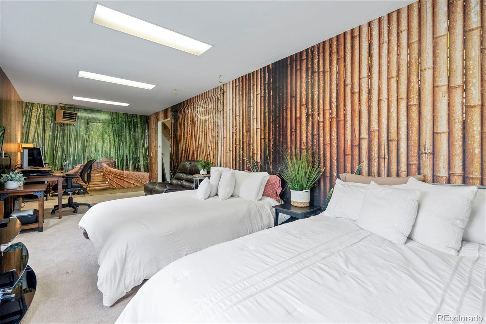 Bedroom with two white beds, bamboo murals, a desk, and a leather armchair.