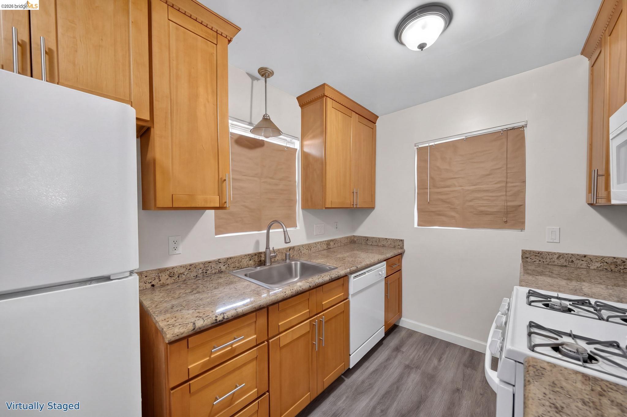 Kitchen with honey-toned cabinets, granite counters, and a stainless sink.