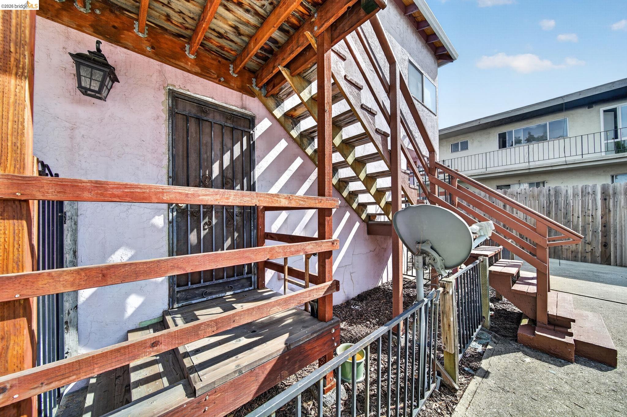 Building exterior with wooden stairs and railings leading to an upper-level entrance.