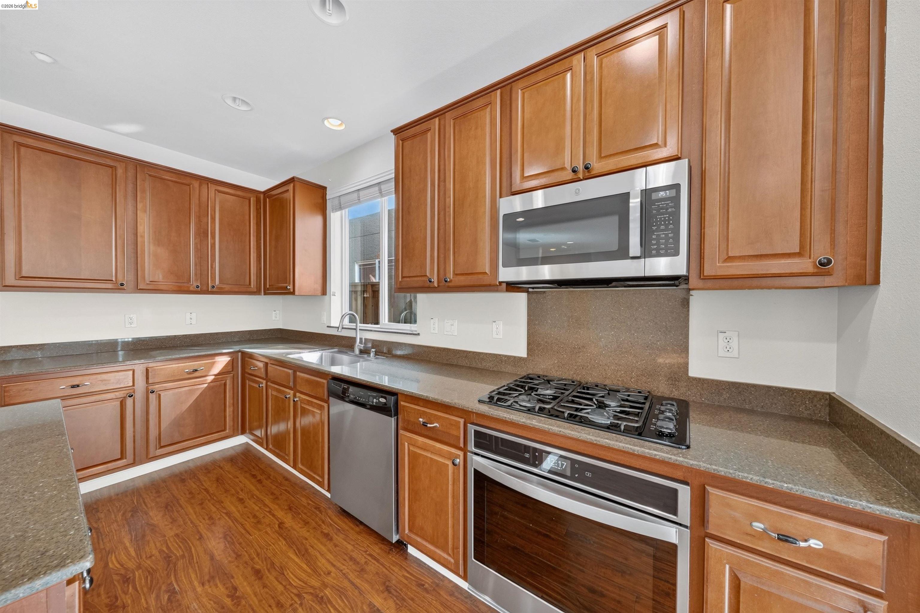 Kitchen with warm wood cabinets, granite counters, and stainless steel appliances.