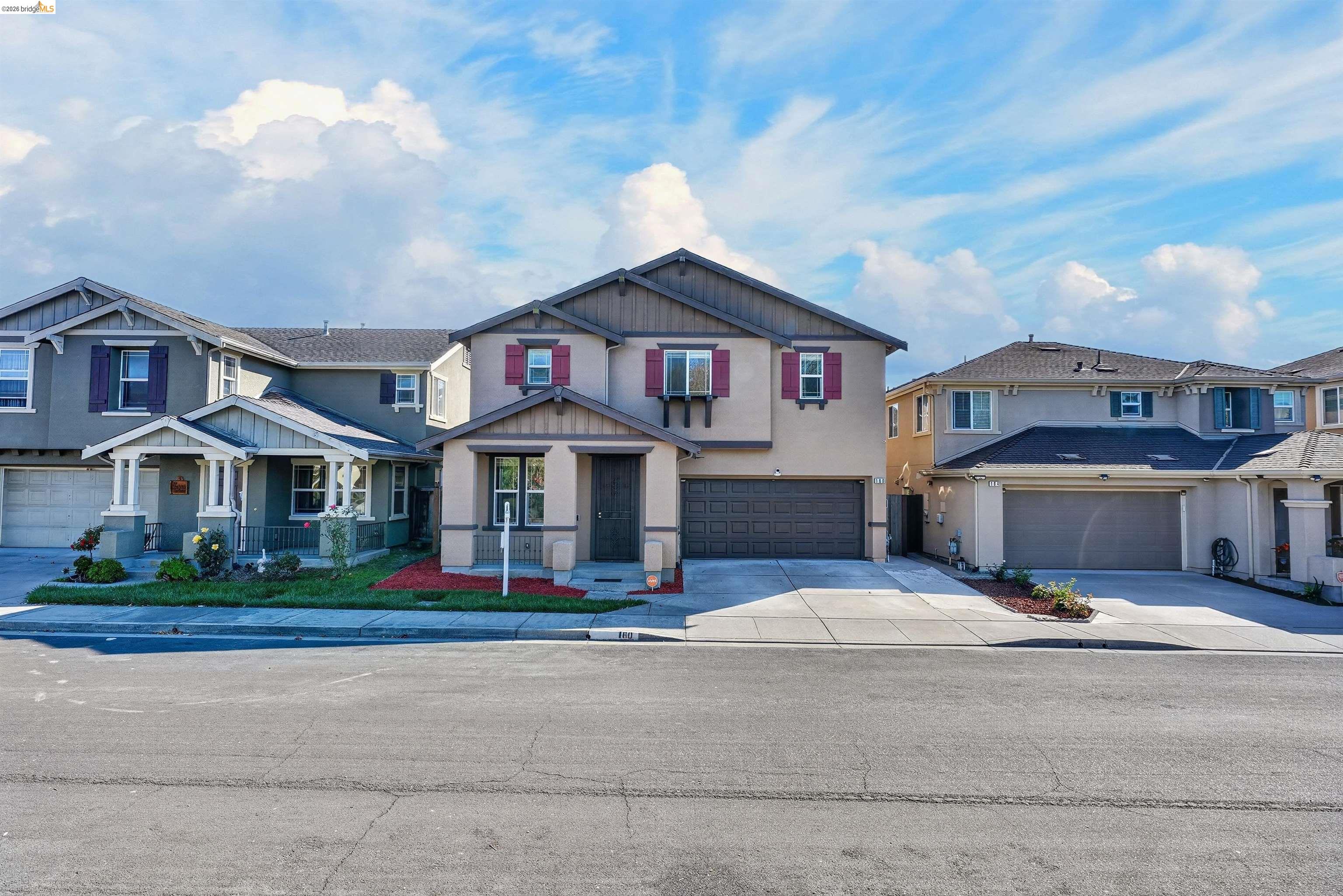Two-story beige home with burgundy shutters, a double garage, and a landscaped front yard.