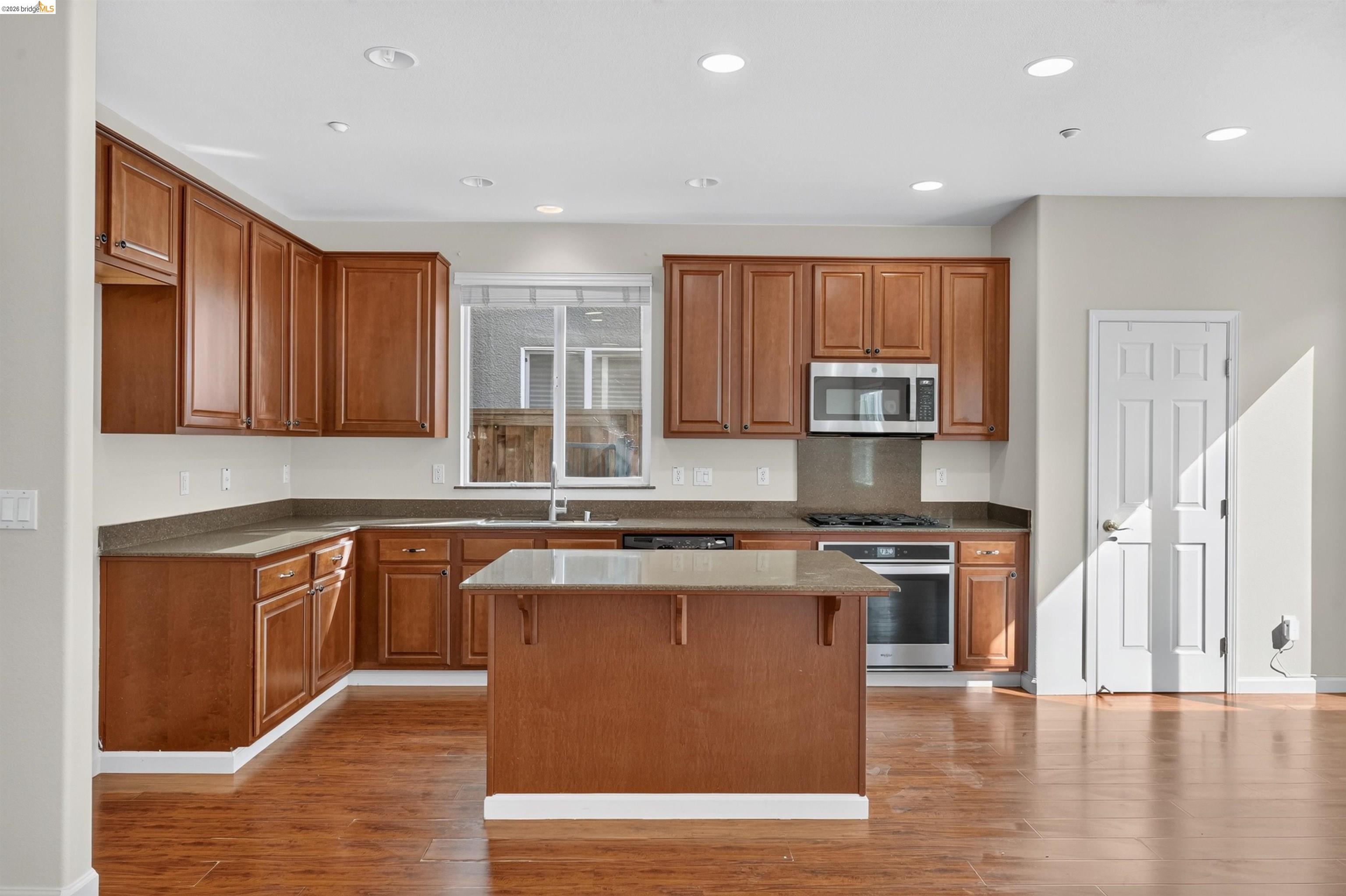 Kitchen with reddish wood cabinets, a central island, and stainless steel appliances.