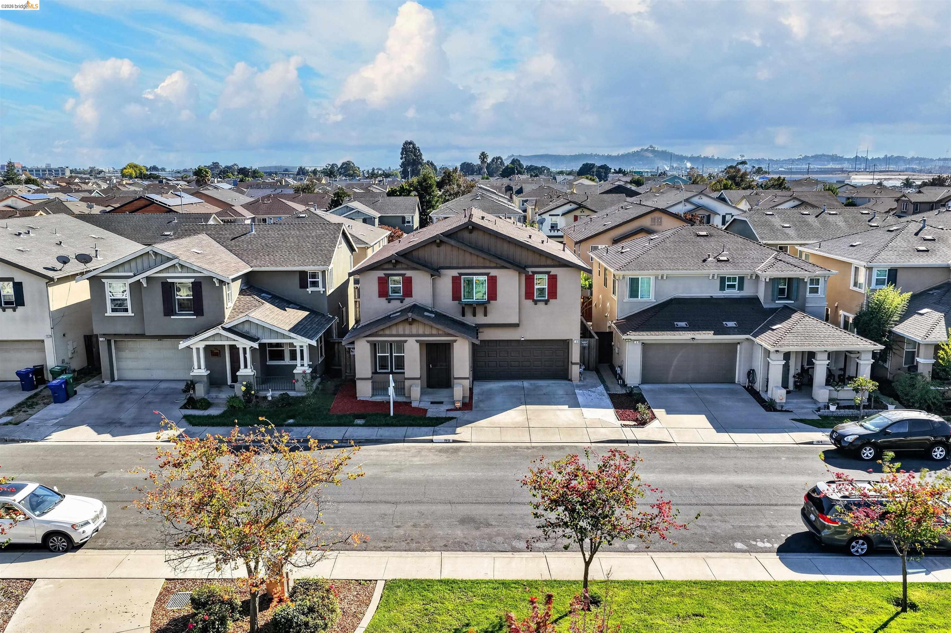 Two-story home with red shutters and attached garage, viewed from above across the street.